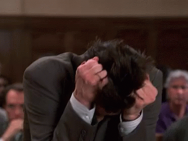 A Man In A Suit Is Scratching His Head GIF