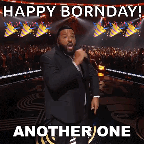 A Man In A Suit Is Singing Into A Microphone With The Words Happy Bornday Another One Behind Him . GIF