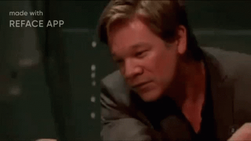 A Man In A Suit Is Sitting At A Table With His Head Resting On His Hand . GIF