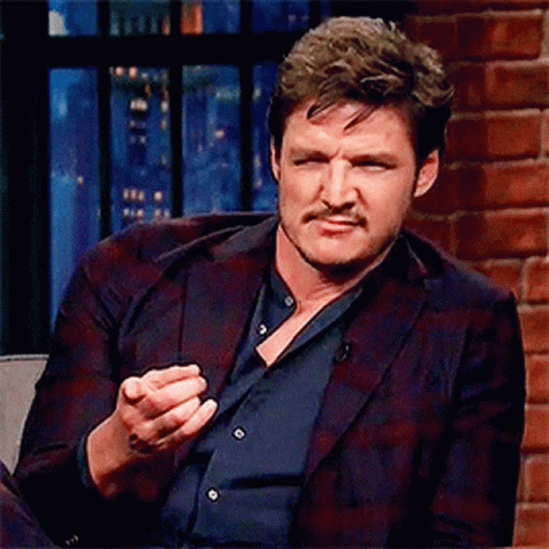 A Man In A Suit Is Sitting In A Chair With His Hand Out . GIF