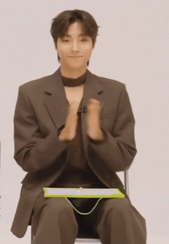 A Man In A Suit Is Sitting In A Chair With His Hands Folded GIF