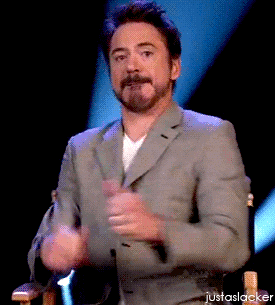 A Man In A Suit Is Sitting In A Chair With His Hands In The Air And The Words Justaslacker Below Him GIF