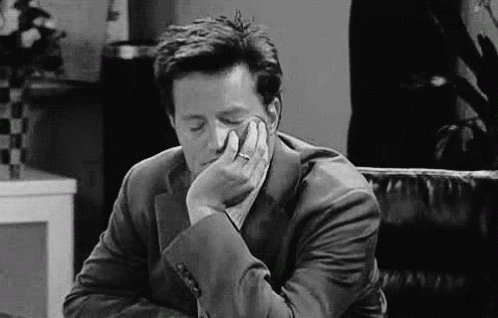 A Man In A Suit Is Sitting In A Chair With His Head Resting On His Hand . GIF