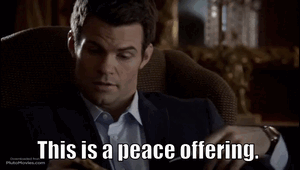 A Man In A Suit Is Sitting In A Chair With The Words This Is A Peace Offering GIF