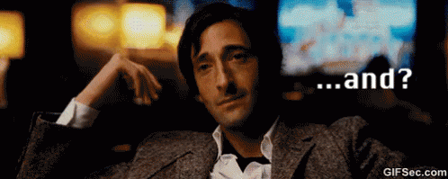A Man In A Suit Is Sitting In A Dark Room With The Words " And " On The Bottom GIF