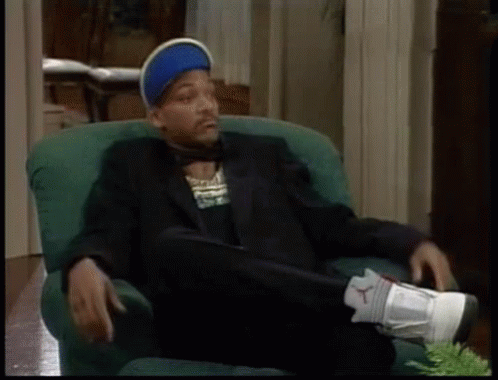 A Man In A Suit Is Sitting In A Green Chair GIF