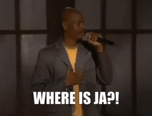 a man in a suit is sitting in front of a microphone and says `` help me ja rule '' .