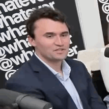 A Man In A Suit Is Sitting In Front Of A Microphone And Talking . GIF
