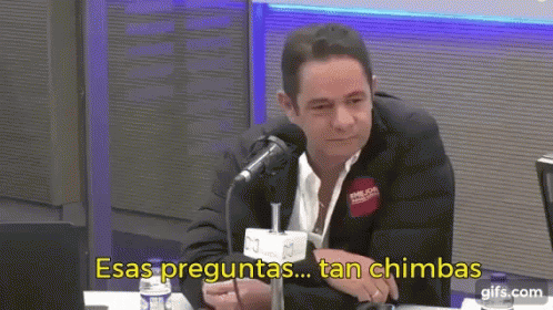 a man in a suit is sitting in front of a microphone with the words esas preguntas tan chimbas written below him