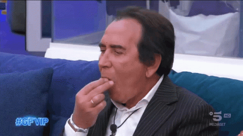 a man in a suit is sitting on a blue couch with #gfvip written on the bottom of the screen