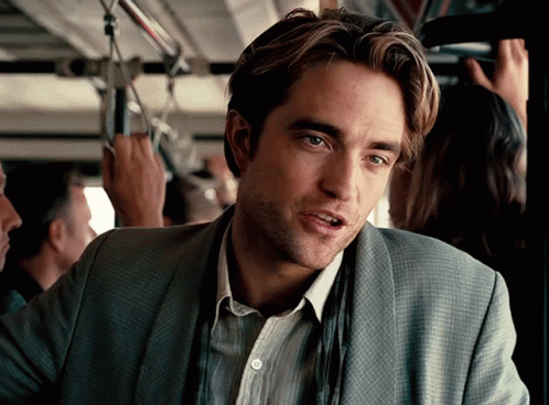 A Man In A Suit Is Sitting On A Bus Looking At The Camera GIF