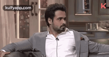 A Man In A Suit Is Sitting On A Couch With His Arms Crossed . GIF