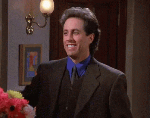 A Man In A Suit Is Smiling And Holding Up A Sign That Says " I Like " GIF