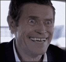 A Man In A Suit Is Smiling And Making A Funny Face In A Car . GIF