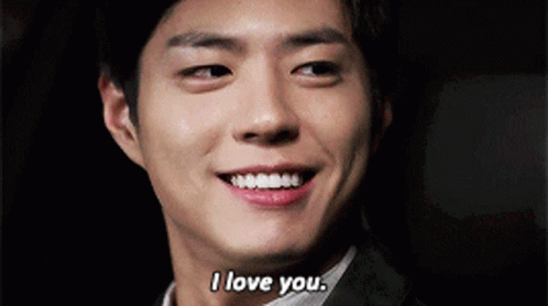 A Man In A Suit Is Smiling And Saying I Love You . GIF