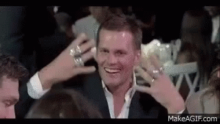Man In Suit Smiling In Crowd With Hands To Head GIF