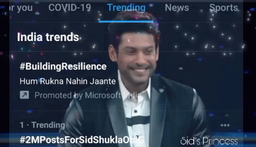 A Man In A Suit Is Smiling In Front Of A Screen That Says Trending India Trends GIF