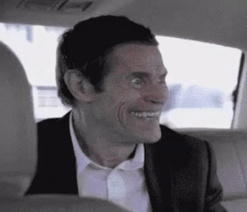 A Man In A Suit Is Smiling In The Back Seat Of A Car . GIF