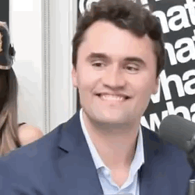 A Man In A Suit Is Smiling Into A Microphone . GIF