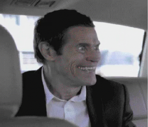 A Man In A Suit Is Smiling While Sitting In The Back Seat Of A Car GIF