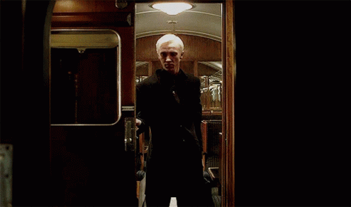 a man in a suit is standing in a dark room behind a door .
