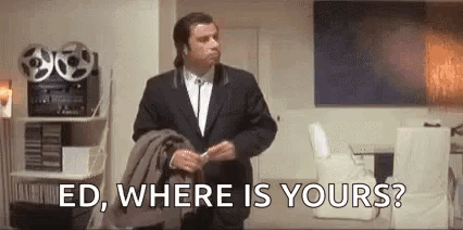 A Man In A Suit Is Standing In A Living Room Holding A Jacket And Talking To Someone . GIF