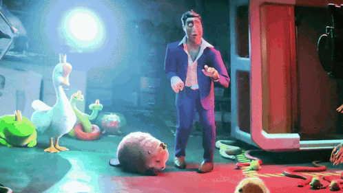A Man In A Suit Is Standing In A Room Surrounded By Stuffed Animals Including A Duck And A Snake GIF