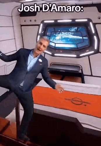 A Man In A Suit Is Standing In A Room With The Words Josh D' Amaro On The Bottom GIF