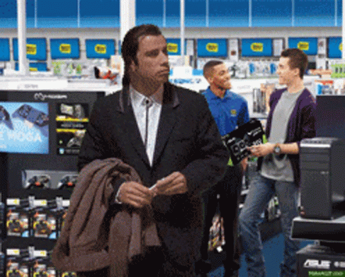 A Man In A Suit Is Standing In A Store Looking At Something GIF