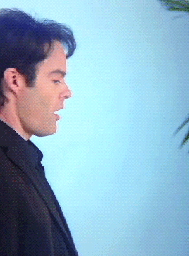 A Man In A Suit Is Standing In Front Of A Blue Background GIF