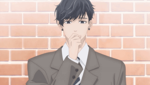 A Man In A Suit Is Standing In Front Of A Brick Wall With His Hand On His Chin GIF