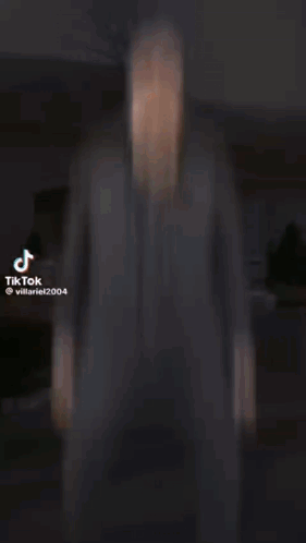 A Man In A Suit Is Standing In Front Of A Building In A Video . GIF