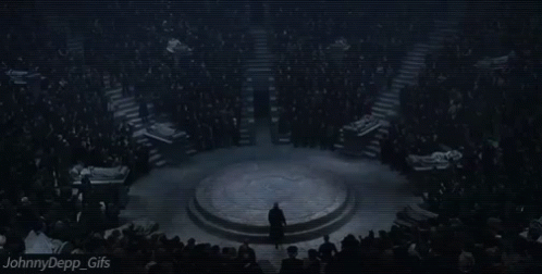 A Man In A Suit Is Standing In Front Of A Crowd Of People . GIF
