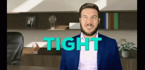 A Man In A Suit Is Standing In Front Of A Desk With The Word Tight Behind Him . GIF