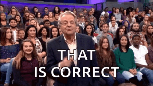 A Man In A Suit Is Standing In Front Of A Large Crowd Of People And Says That Is Correct . GIF