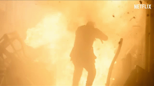 A Man In A Suit Is Standing In Front Of A Large Explosion With Netflix Written On The Bottom GIF