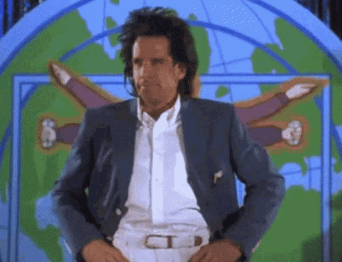 A Man In A Suit Is Standing In Front Of A Map Of The World GIF