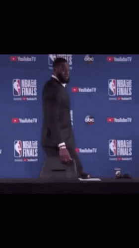 a man in a suit is standing in front of a nba finals sign