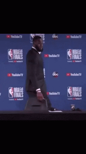 a man in a suit is standing in front of a nba finals wall