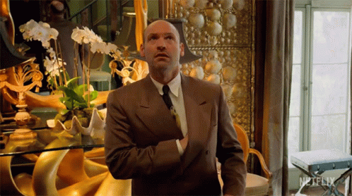 A Man In A Suit Is Standing In Front Of A Netflix Sign GIF