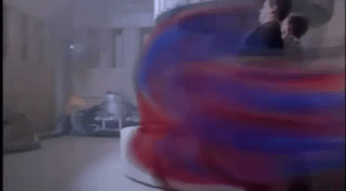 A Man In A Suit Is Standing In Front Of A Red And Blue Object In A Room . GIF