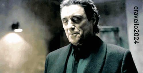 A Man In A Suit Is Standing In Front Of A Sign That Says Cavelli202024 GIF