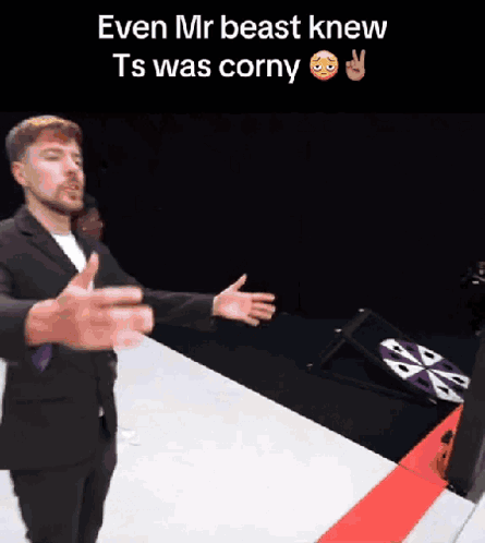 A Man In A Suit Is Standing In Front Of A Sign That Says Even Mr Beast Knew Ts Was Corny . GIF