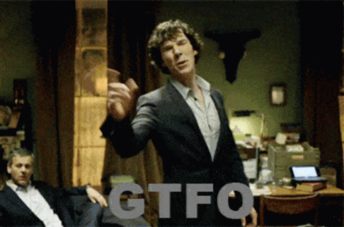 A Man In A Suit Is Standing In Front Of A Sign That Says Gtfo On It GIF