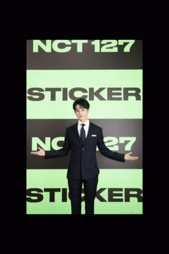 A Man In A Suit Is Standing In Front Of A Sign That Says Nct127 Sticker GIF