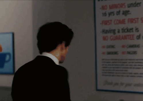 A Man In A Suit Is Standing In Front Of A Sign That Says " No Smoking " GIF