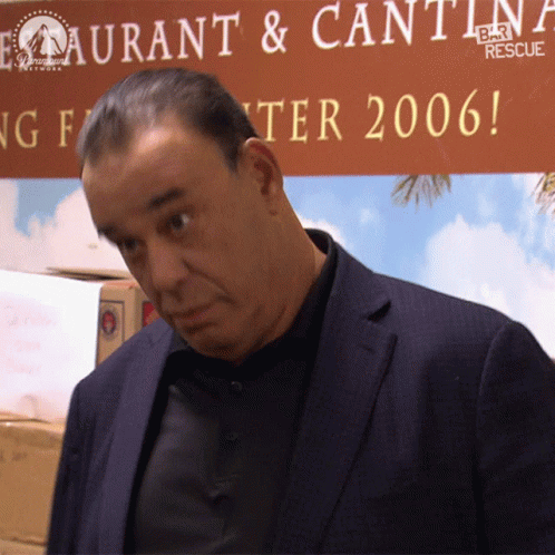Man In Suit In Front Of Restaurant & Cantina Bar Rescue Sign GIF