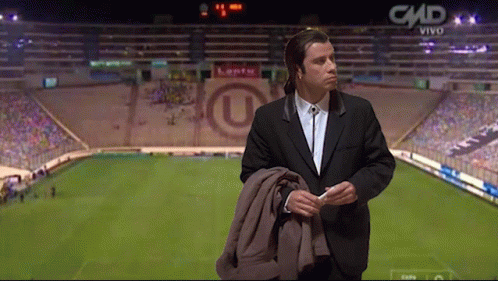 A Man In A Suit Is Standing In Front Of A Stadium That Says Cmd On The Bottom GIF
