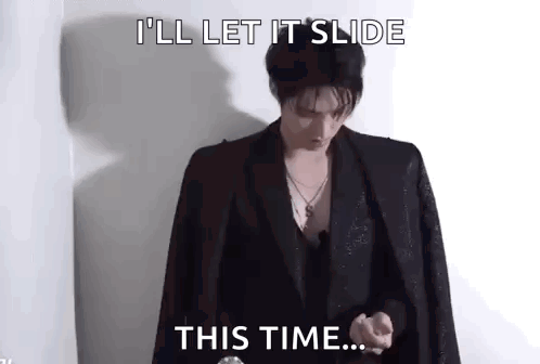 A Man In A Suit Is Standing In Front Of A Wall And Saying `` I 'Ll Let It Slide This Time ... '' . GIF