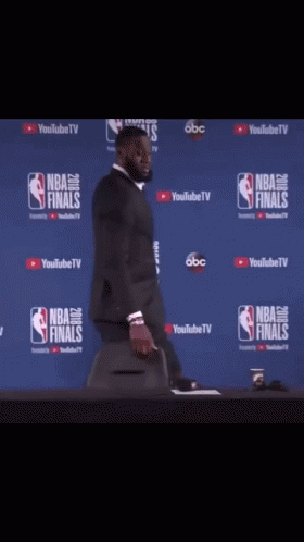 a man in a suit is standing in front of a wall that says nba finals on it